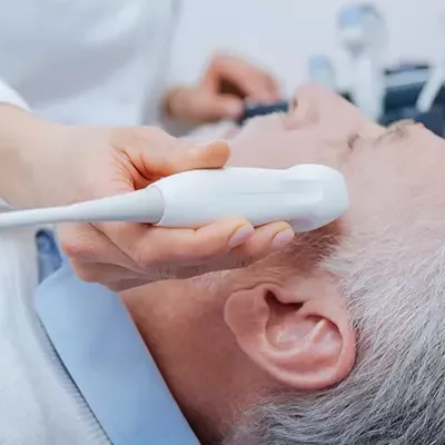 Ultrasound scanning of head vessels. Skilled experienced positive doctor working in the hospital while providing ultrasound head vessels examination and using ultrasound equipment